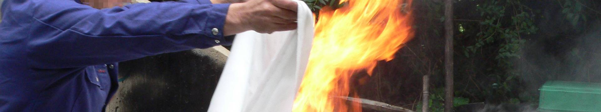 Un hombre está usando una manta de fuego para extinguir el fuego.