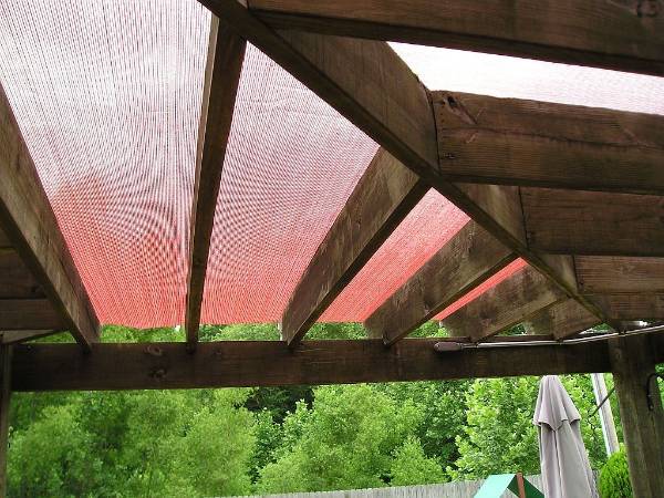 Tela de proteção solar de fibra de vidro é instalado cobrir a pérgula de madeira.
