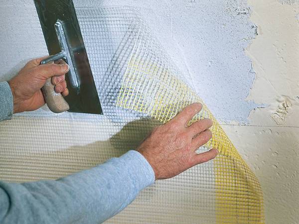 Enlucido la pared con malla de fibra de vidrio amarilla.